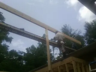 Carpenter setting a ridge beam over a new addition frame — Ice Dam Removal by Roofing Brothers in Arimo