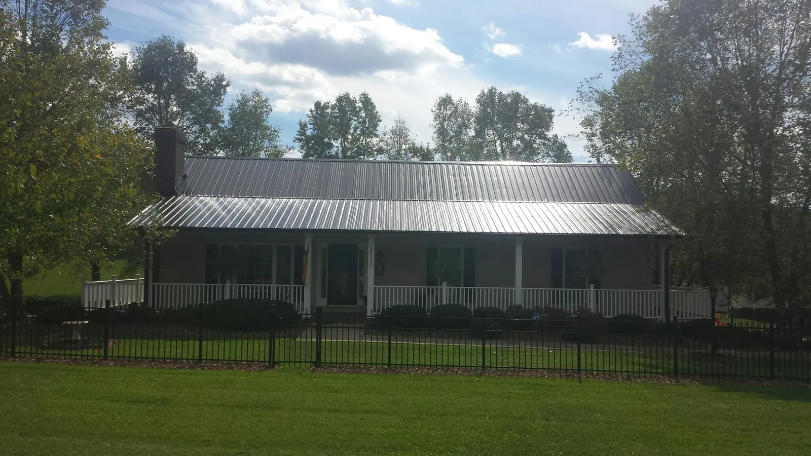 Gray metal roof on a brick ranch with a full width front porch — Gutter Guard Installation work by our crew in Arimo