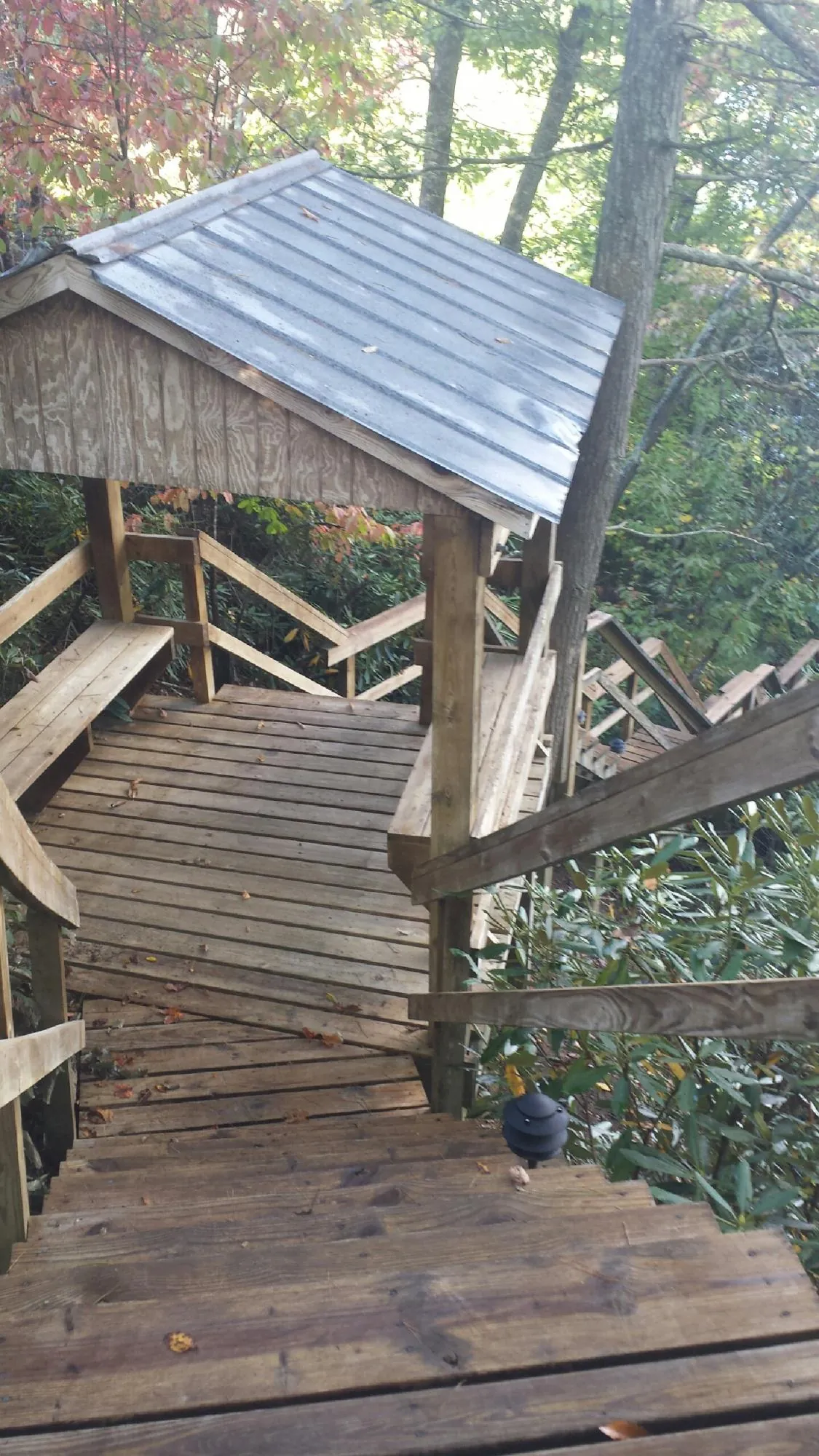 Metal roofed shelter over wooden steps on a wooded walkway — Skylight Repair & Installation work by our crew in Arimo