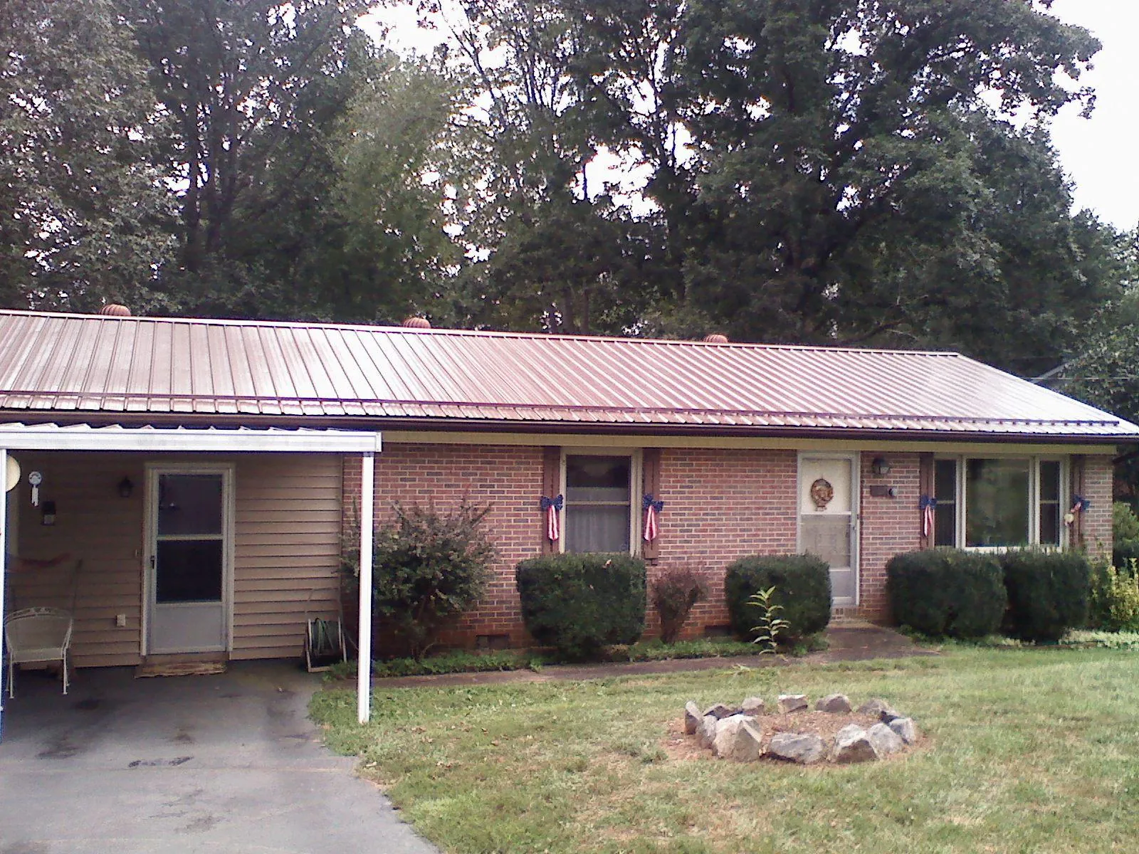 Bronze metal roof and carport on a brick ranch home — Roof Repair work by our crew in Arimo