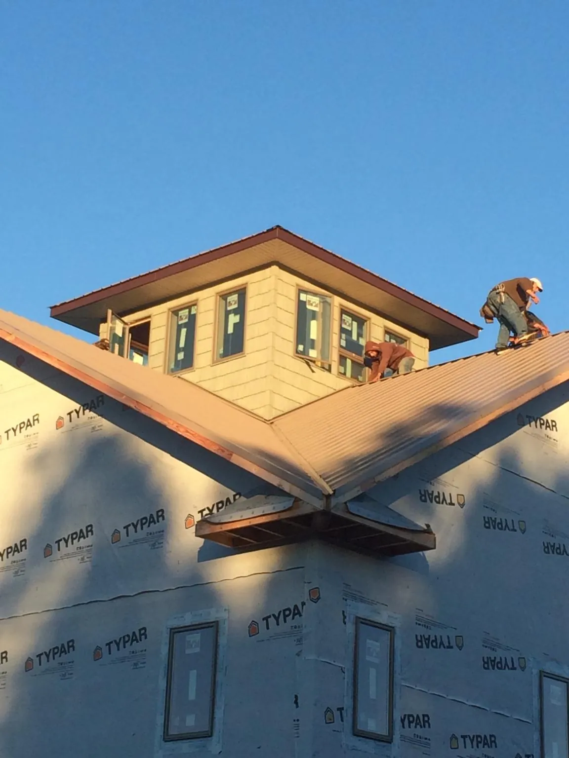 Roofers working around a rooftop cupola on a new metal roof at sunset — Roof Waterproofing in Arimo by Roofing Brothers